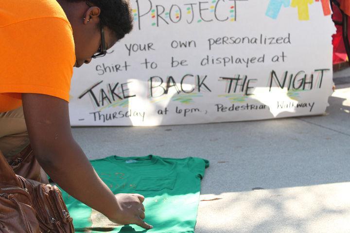Tia Street, freshman in pre-professional interest, decorates a shirt as part of the Clothesline Project on the Pedestrian Mall on Monday, Oct. 24. All the shirts decorated during the project, which lasted all week, were displayed as part of Take Back the Night on Thursday, Oct. 27.