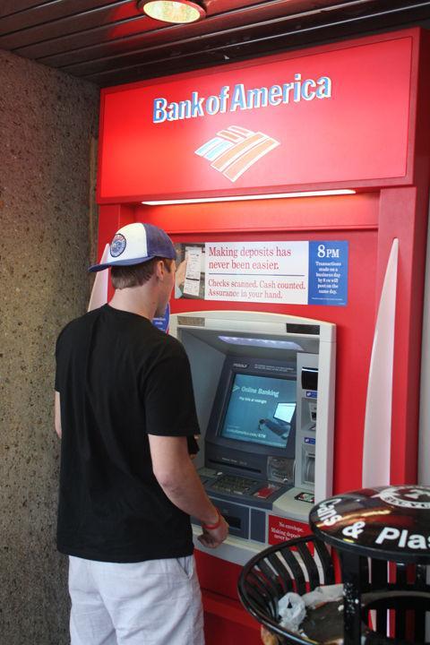 Steven Lewandowski, sophomore in public relations, withdraws money from an ATM at the Money Wall on Thursday, Nov. 10. Banks such as Bank of American have been forced to charge higher fees due to a national law which prohibits them from automatically charging fees when a customer overdrafts.