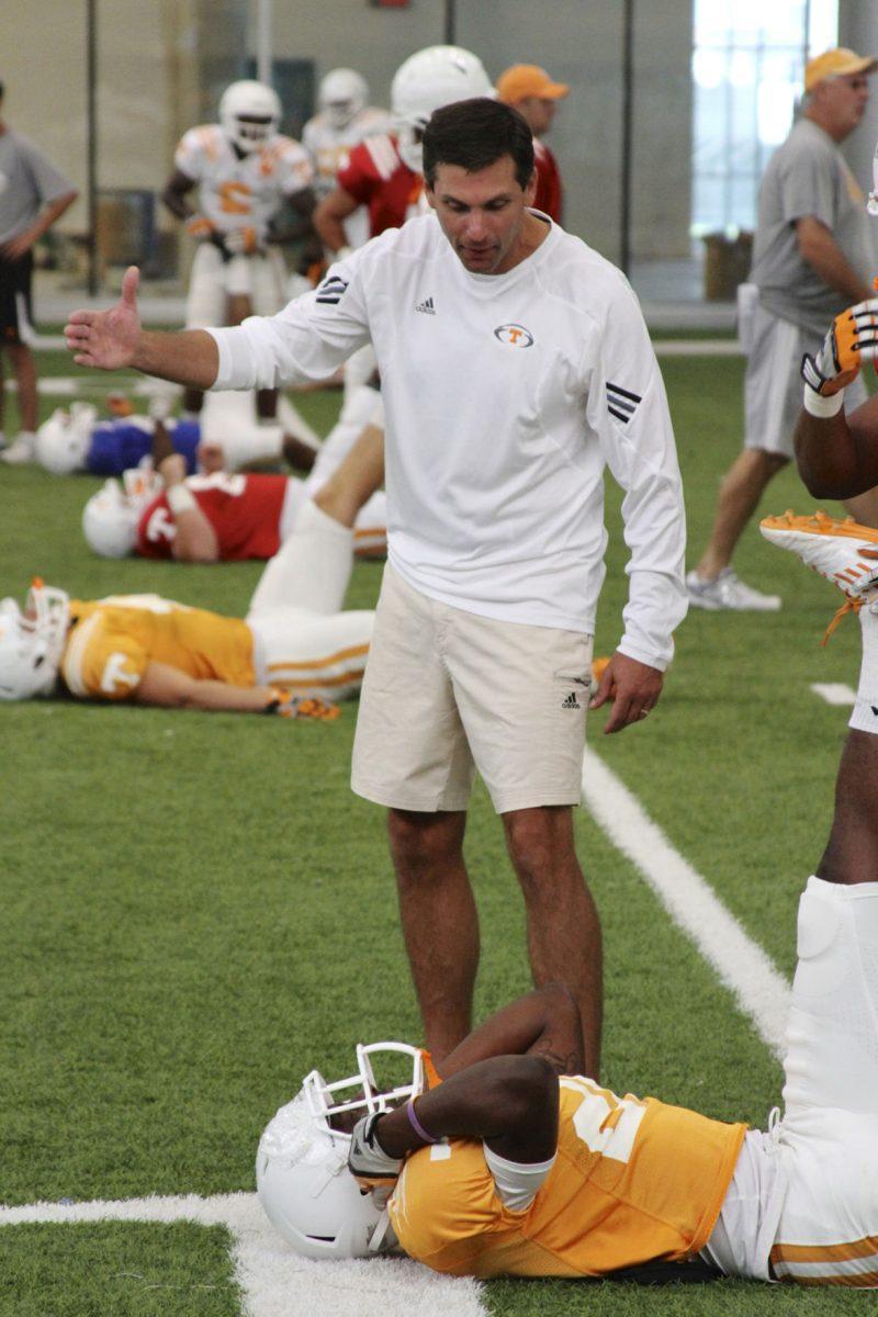 Head coach Derek Dooley speaks to one of his stretching players during practice on Aug. 27.