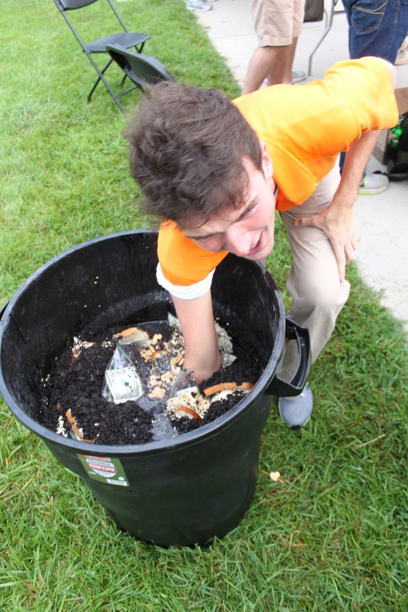 Michael Porter, senior in political science, daringly sticks his hand into a trashcan searching for money as a part of the Volunteer Vengeance challenge at the Involvement Fair on Aug. 23.