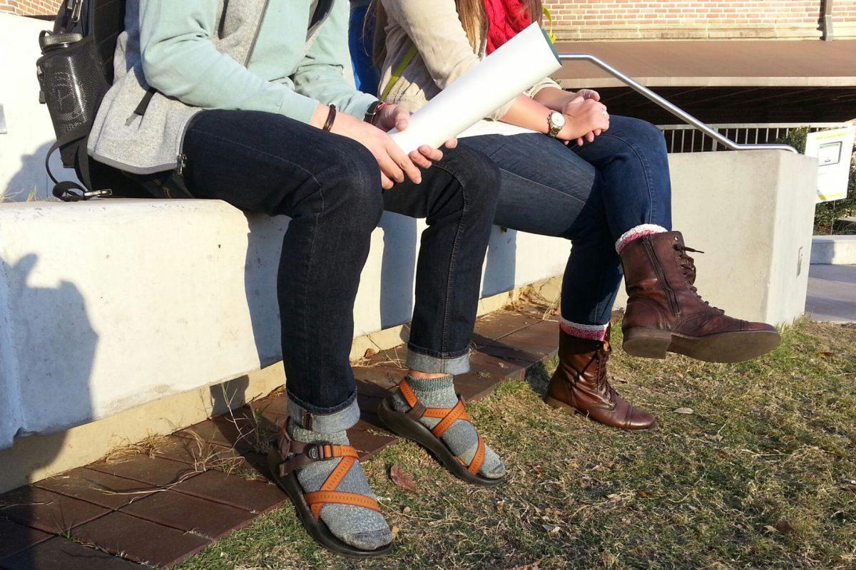 Sophomore Hayden Zelem, right, sits with Gracyn Garrettt, junior in psychology, outside of AMB on Wednesday afternoon. Zelem wears grey socks with his orange and brown Chacos as part of his comfortable attire for the day. "It's the perfect weather to wear them and more people should be supporting the look," said Zelem.