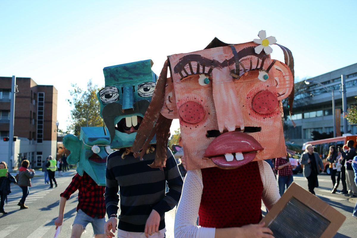 Students wearing "hill-billie" masks walk in the homecoming parade with the Wayne White-inspired float on Friday. The Alpha Delta Pi sorority and Pi Kappa Phi fraternity won first place for best large float.