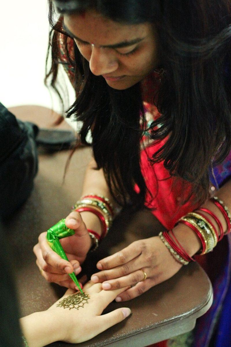 Snigdha Sewlikar, graduate research student in food science, decorates a hand with henna at the Diwali festival at the UC on Sunday.