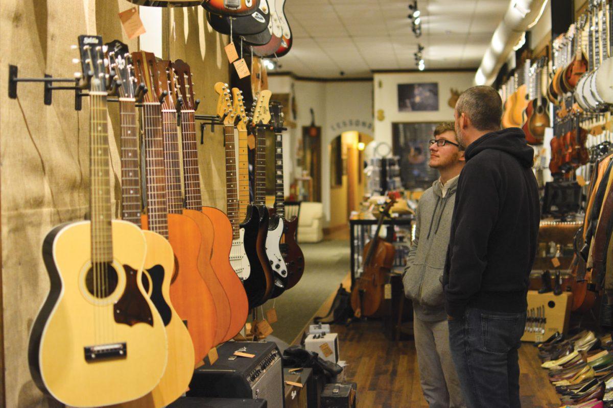 Josh Sidman, right, owner of The Parlor, assists a customer as he admires the assorted instruments inside the store on Wednesday.