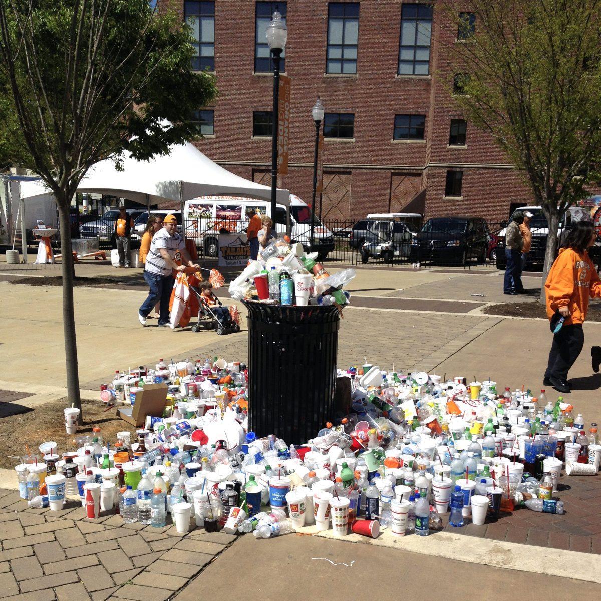 Attendees of the April 21, 2013 Orange and White Game stack excess trash around an overflowing trash can. Recycling services aims to make Neyland Stadium a zero waste venue by 2015