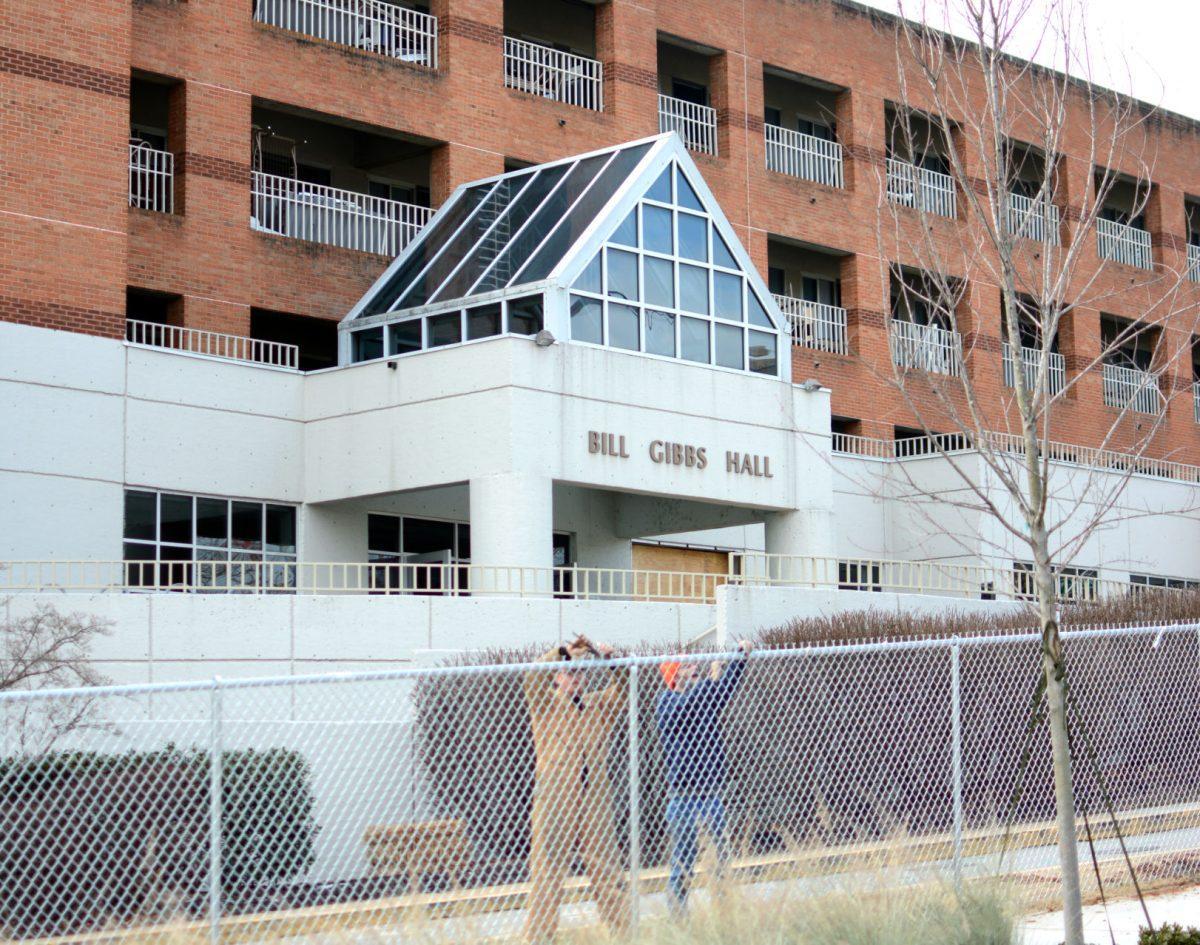 Two construction workers set up fence outside of Gibbs on Jan. 9 in preparation for the demolition of Gibbs Hall and Stokely Athletic Center. The demolition is the next step in the university's plan to redesign residential halls.