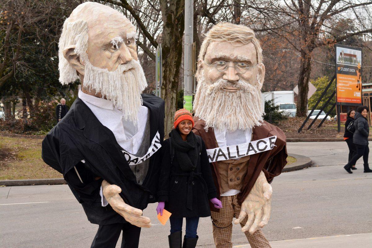 Amber Moore, senior in microbiology, eagerly poses with the giant puppets of Charles Darwin and Alfred Russell Wallace, a colleague of Darwin, outside of Walters Life Sciences on Thursday.