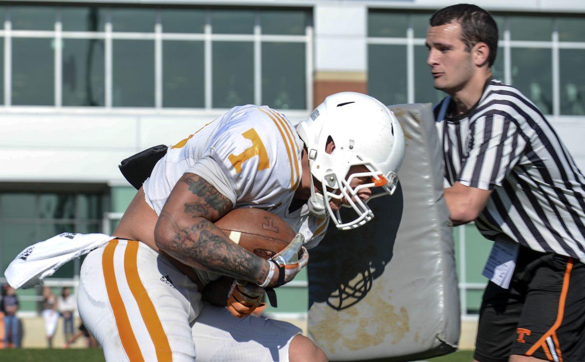 Redshirt sophomore running back Alden Hill (30) lowers his shoulders and tackles the practice pads during the spring football practice in the Haslam field on Tuesday.