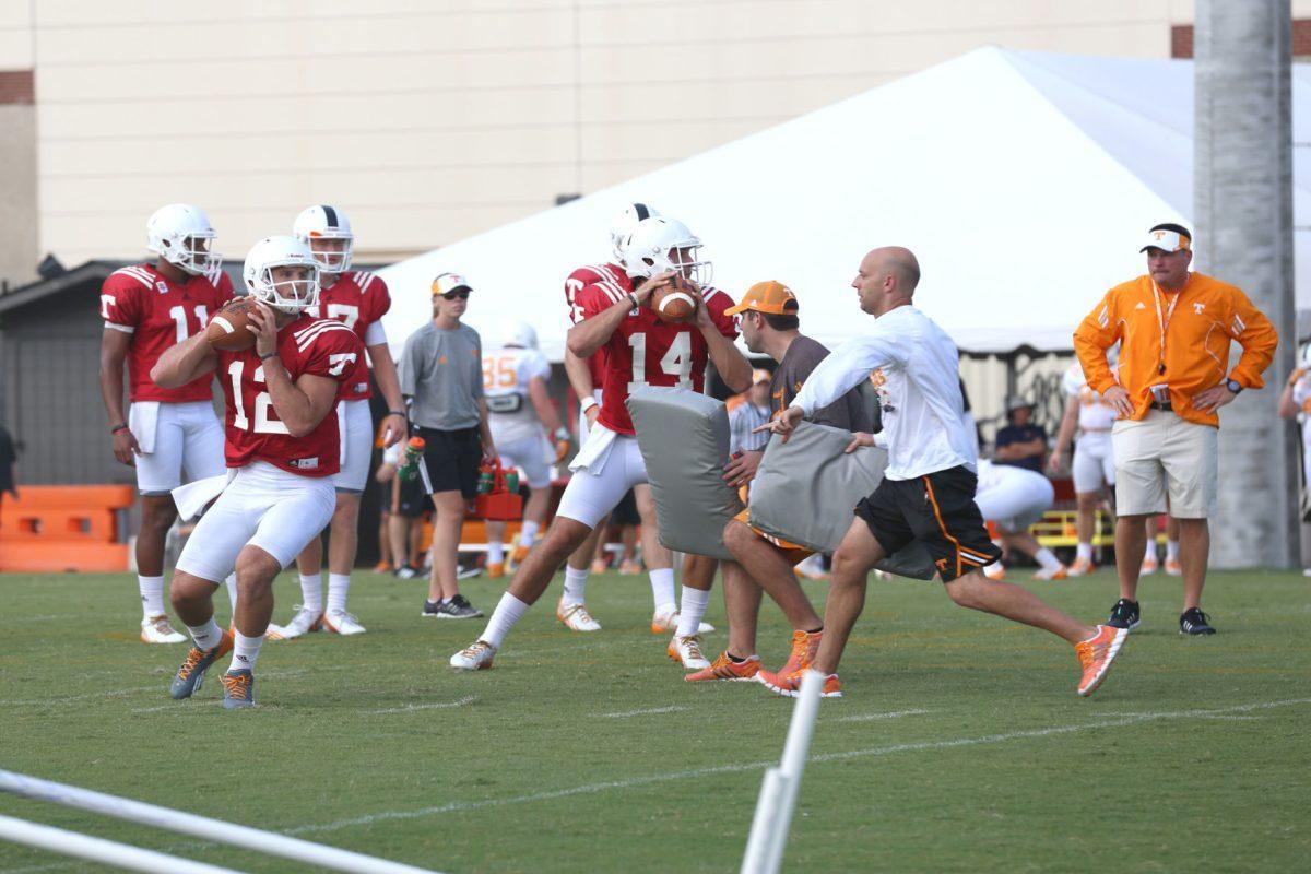 Offensive Coordinator Mike Bajakian works with quaterbacks Nathan Peterman (L) and Justin Worley (R) during fall football camp on Aug. 3, 2014