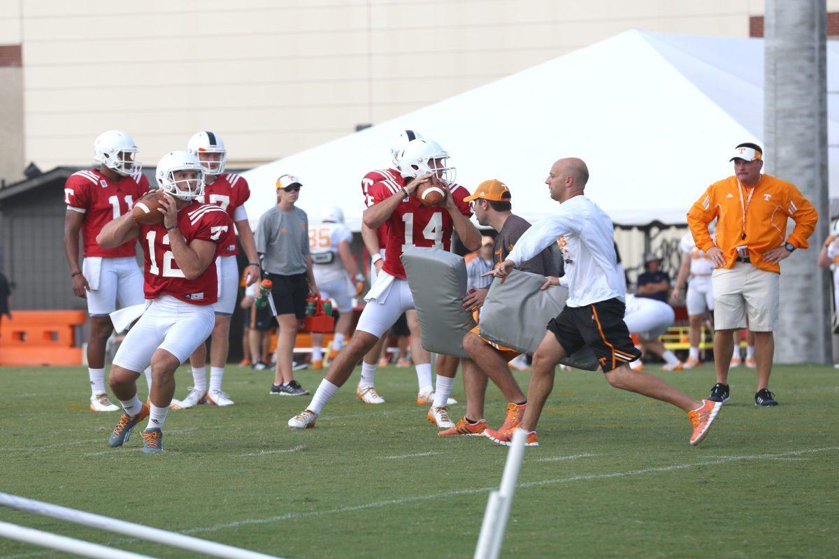 Offensive Coordinator Mike Bajakian works with quaterbacks Nathan Peterman (L) and Justin Worley (R) during fall football camp on Aug. 3, 2014