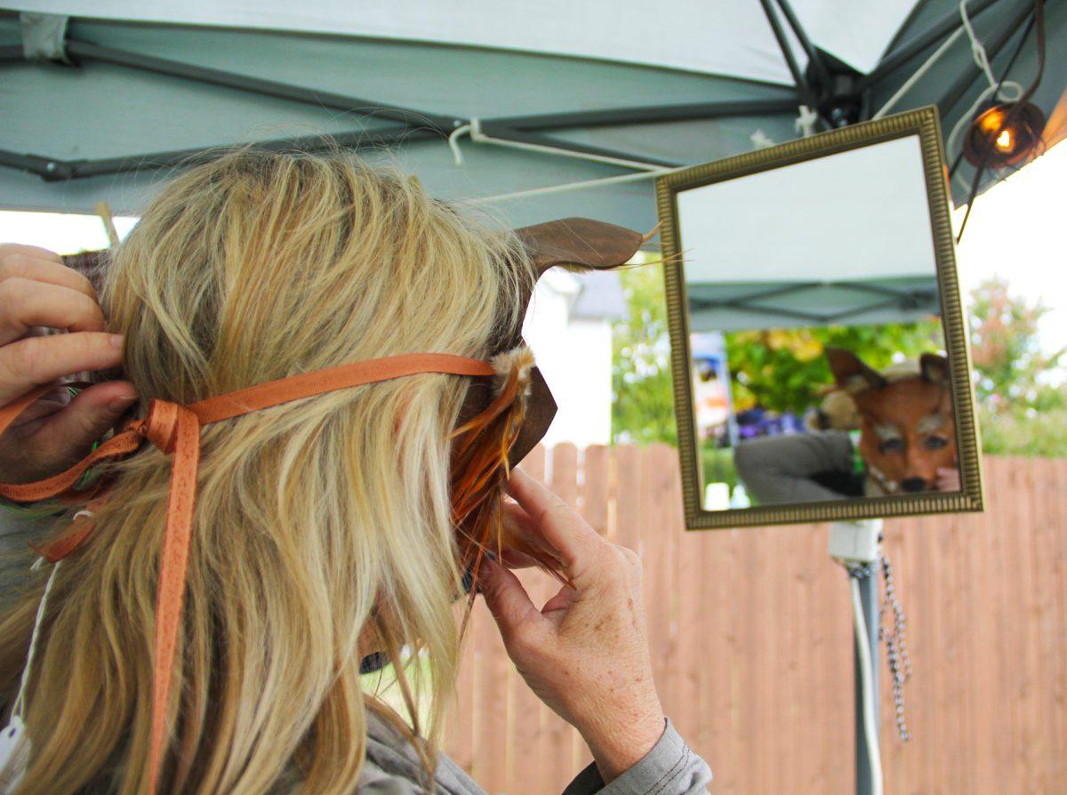 A woman tries on a fox mask made by a local artist at ARToberfest held at the Fourth and Gill neighborhood Saturday evening.