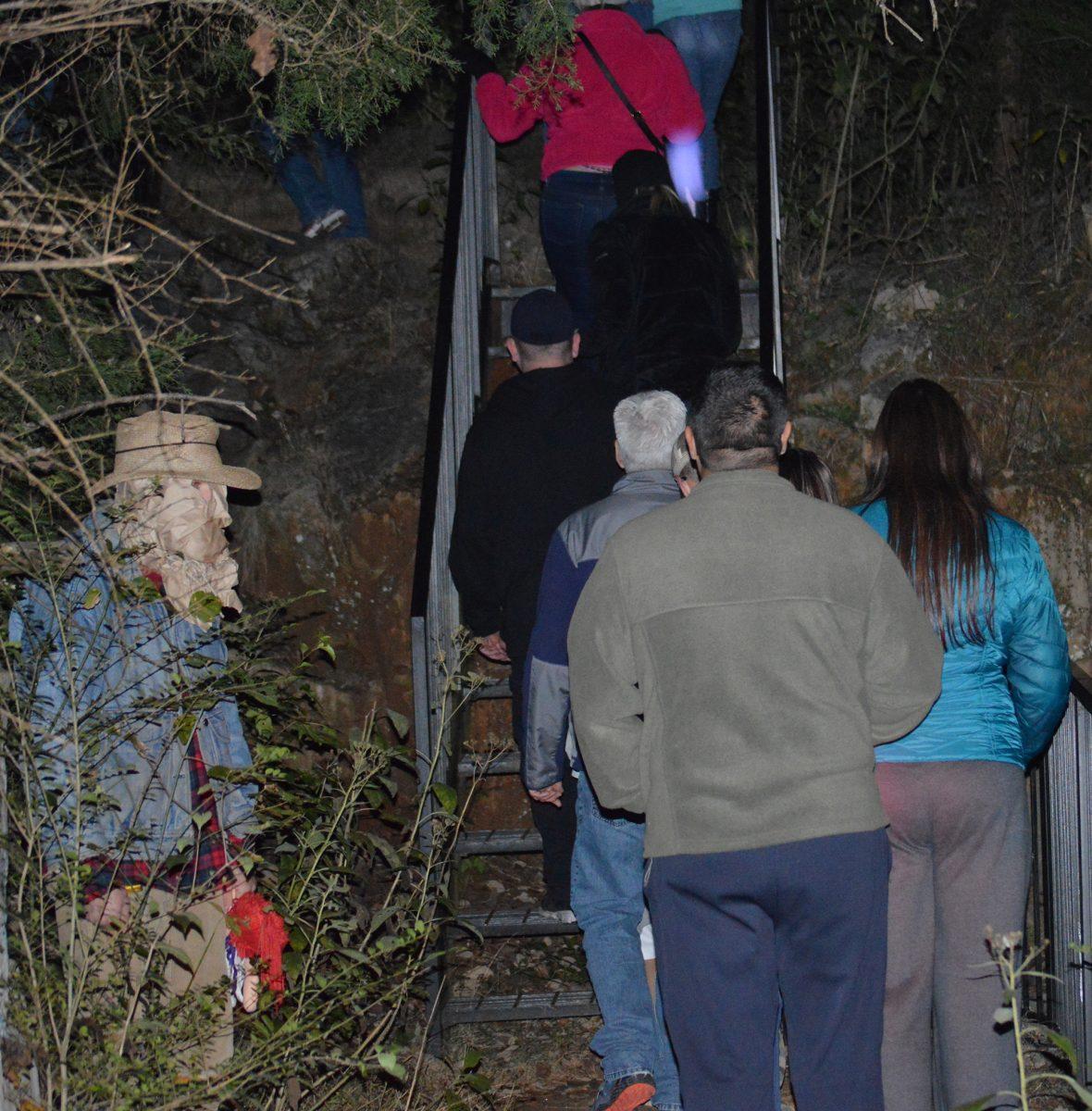 A man stands off the path in a paper mask, holding a cloth doll, as a part of the lantern tours in Ijams Nature Center on Thursday.