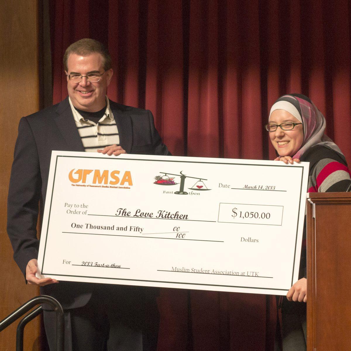 The President of Muslim Student Association gives Patrick Riggins, the President of The Love Kitchen, the money donated from the Muslim Student Association Fast-a-thon event in the UC Ballroom March 14.