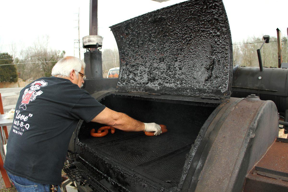 Walter Love, owner of Love That BBQ, places sausage on the grill to smoke before they get deep fried on Tuesday.
