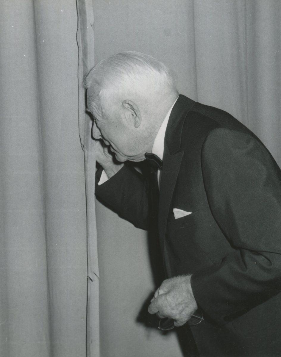 Clarence Brown peeks through the curtains at the audience gathered for the grand opening of his namesake theatre company at UT in 1970.