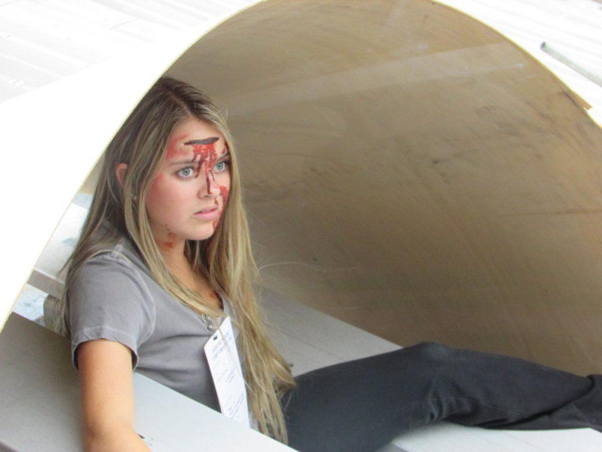 Peyton Lee, junior nursing student, sits under a piece of "debris" with a simulated forehead wound in Neyland Stadium during UT's emergency drill event that involved more than 300 people on Friday.