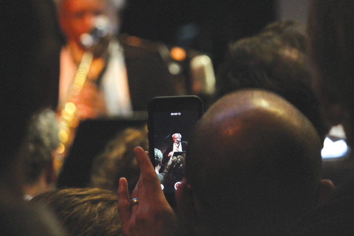 People in the audience recording the Big Ears show performers.