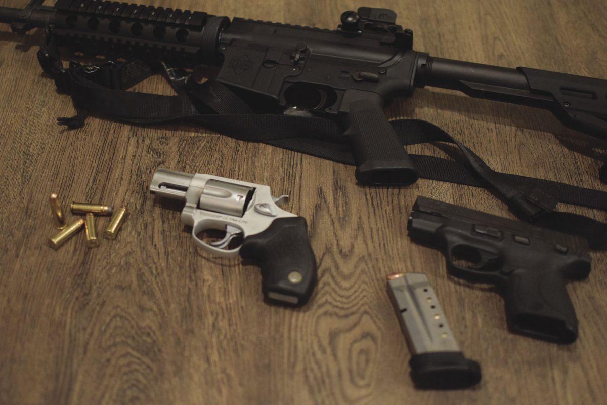 A carbine, a revolver and a semi-automatic handgun on display. 