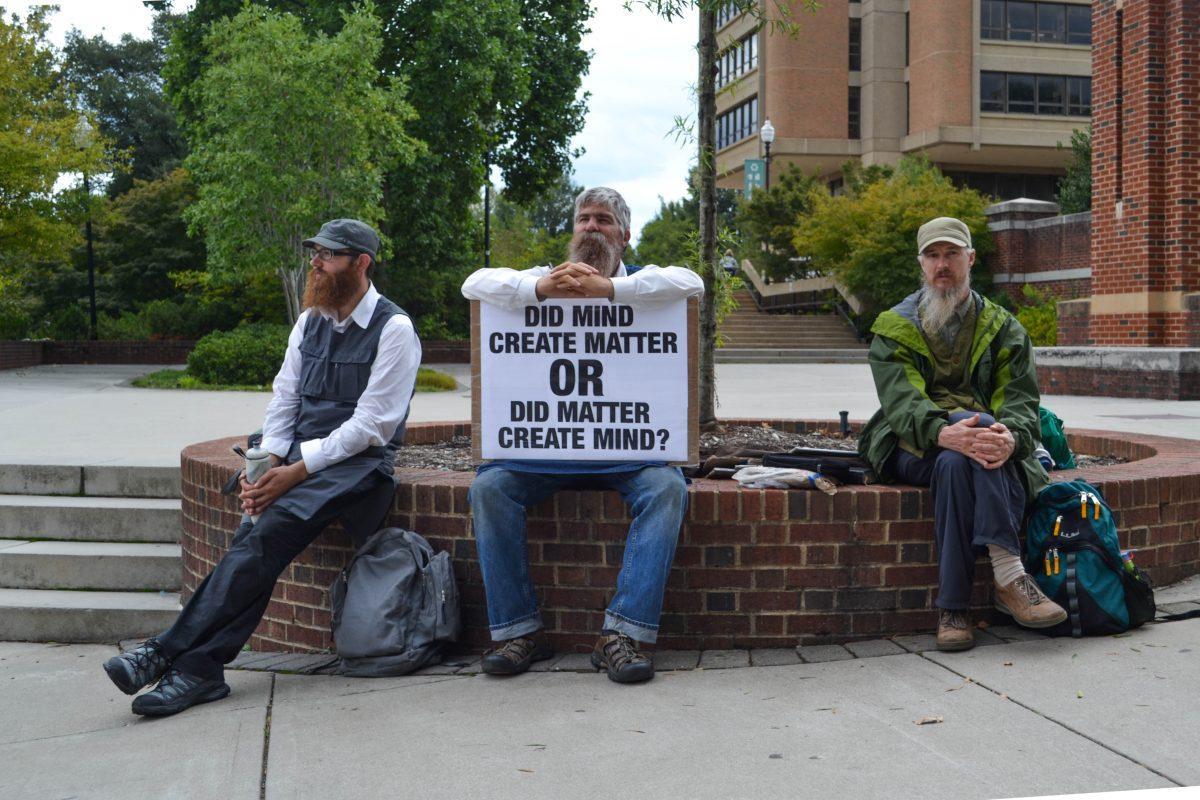 Men on Pedestrian Walkway hold signs asking existential questions to make college students think and spur conversation.