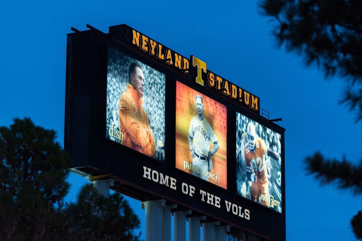 File: Neyland Stadium's JumboTron lit up at night displays portraits of former head coaches Butch Jones and Robert Neyland, and former defensive end Reggie White. 