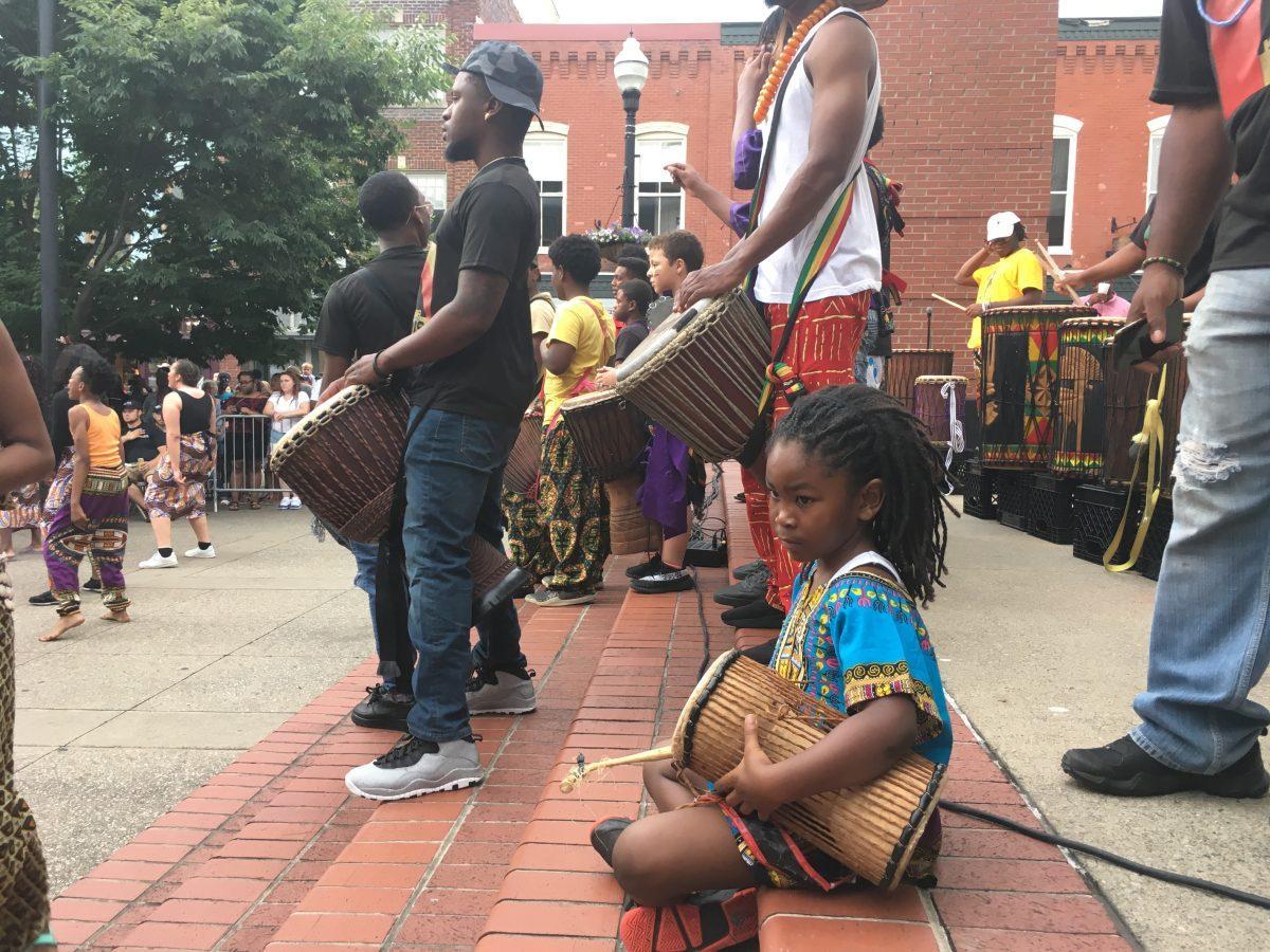 A young child beats their drum in a musical performance with Indigenous Vibes. 