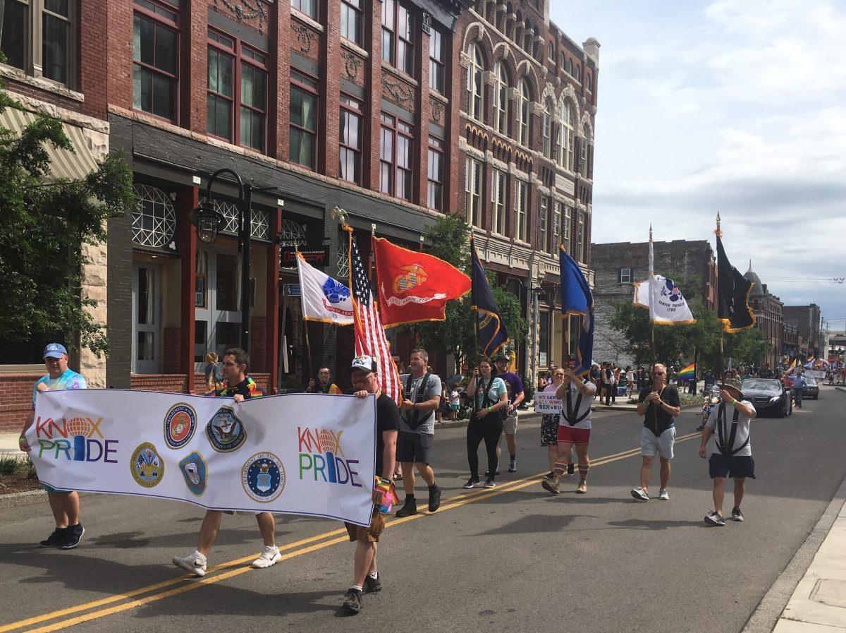 A banner displays the branches of the military, representing the LGBTQ+ members who have served and who are currently serving. 