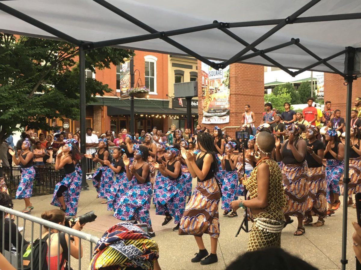 Youth dancers from the Watoto troupe perform, while host Sista Zock films their performance. 
