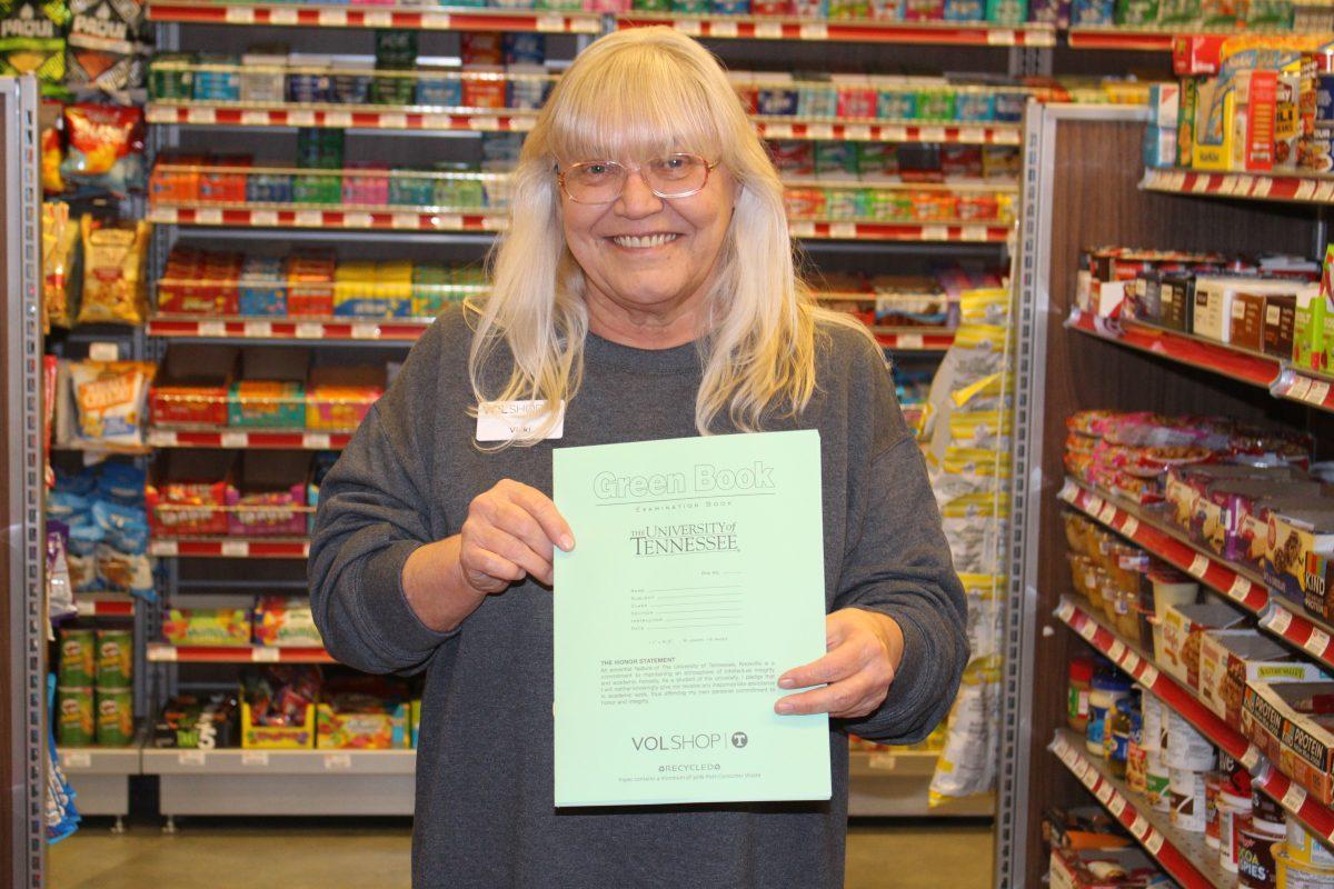 Vicki Smith, manager of VolSnacks, stands in the shop with a Green Book.