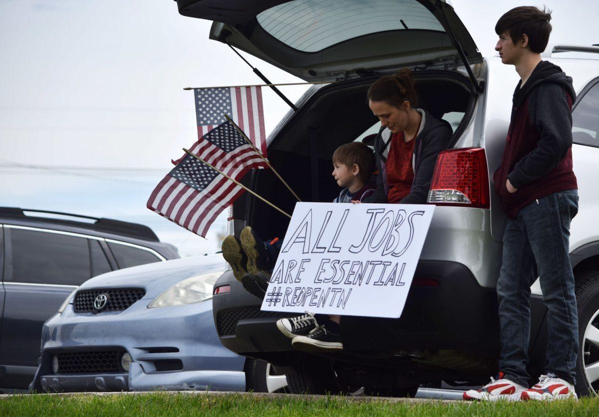 A mother and her children hold up a sign as they stay near their car during the Freedom Rally protest outside of the closed West Town Mall along Kingston Pike on Sunday, April 19, 2020. Protesters in other major Tennessee cities - Nashville, Memphis, Chattanooga, Jackson, Johnson City and Cookeville - also took to the streets to protest.