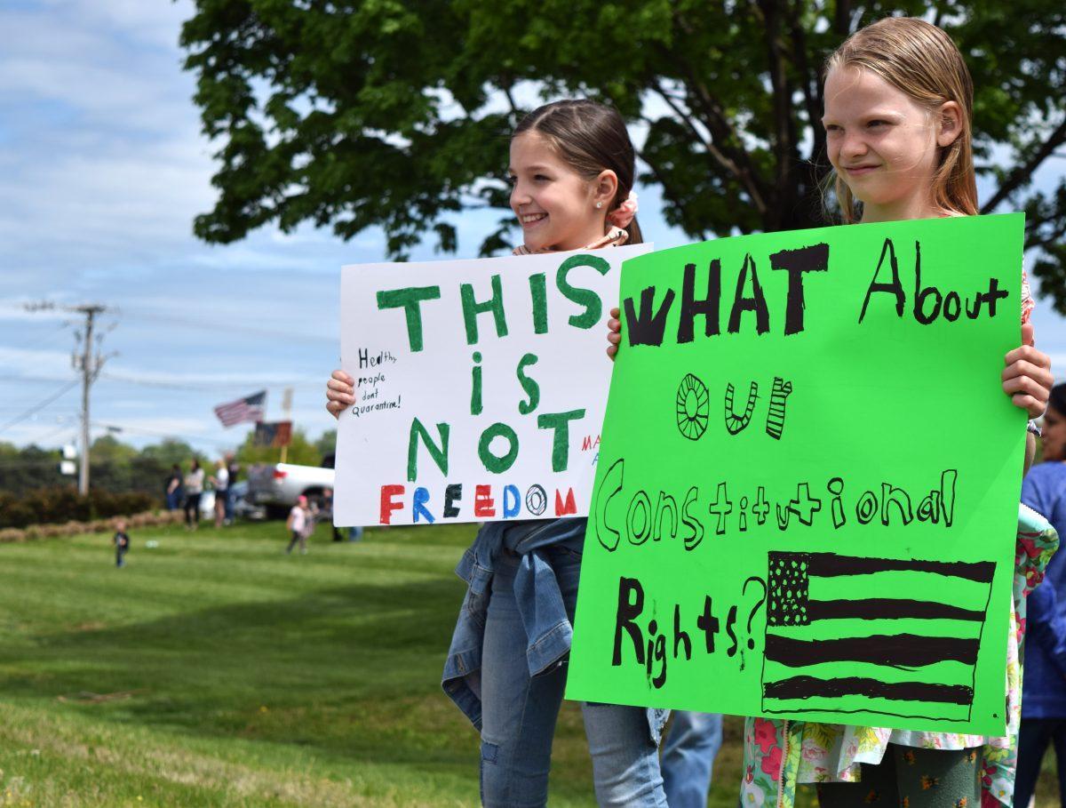 Two young protesters hold up signs next to Kingston Pike outside of West Town Mall at the Knoxville Freedom Rally on Sunday, April 19, 2020. Protests were held in seven other major cities across Tennessee against Governor Bill Lee's mandatory shutdown on nonessential businesses because of the coronavirus pandemic.