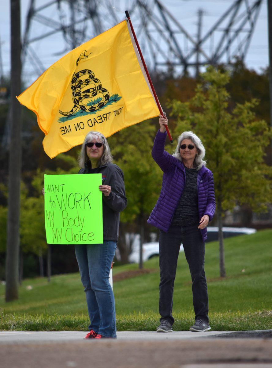 Two protesters stand on the corner of Morrell Road and Kingston Pike outside West Town Mall holding a sign and "Don't Tread on Me" flag during the Knoxville Freedom Rally on Sunday, April 19, 2020. The protest is one of seven in major cities across Tennessee rallying against Governor Bill Lee's mandatory shutdown of nonessential businesses because of the coronavirus outbreak.