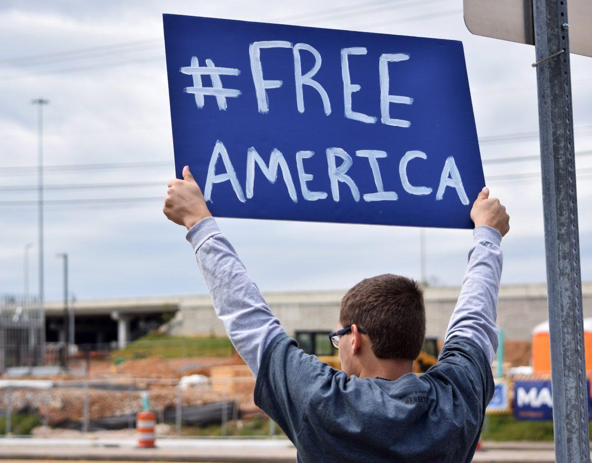 A protester hold up a sign to passing cars during the Knoxville Freedom Rally alongside Kingston Pike next to West Town Mall on Sunday, April 19, 2020. Protesters came together feeling that their Constitutional rights were being infringed upon by Governor Bill Lee's stay-at-home orders and closure of nonessential businesses.