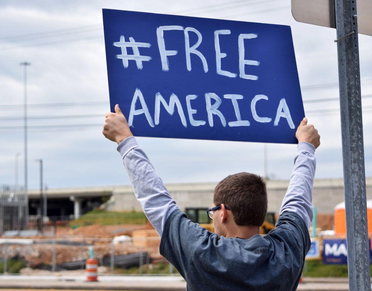 A protester hold up a sign to passing cars during the Knoxville Freedom Rally alongside Kingston Pike next to West Town Mall on Sunday, April 19, 2020. Protesters came together feeling that their Constitutional rights were being infringed upon by Governor Bill Lee's stay-at-home orders and closure of nonessential businesses.