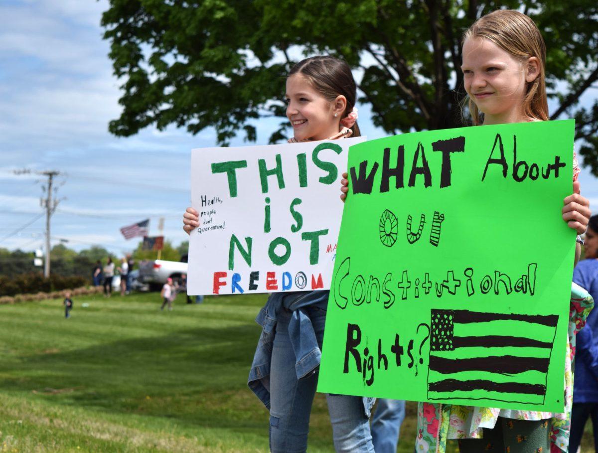 Two young protesters hold up signs next to Kingston Pike outside of West Town Mall at the Knoxville Freedom Rally on Sunday, April 19, 2020. Protests were held in seven other major cities across Tennessee against Governor Bill Lee's mandatory shutdown on nonessential businesses because of the coronavirus pandemic.