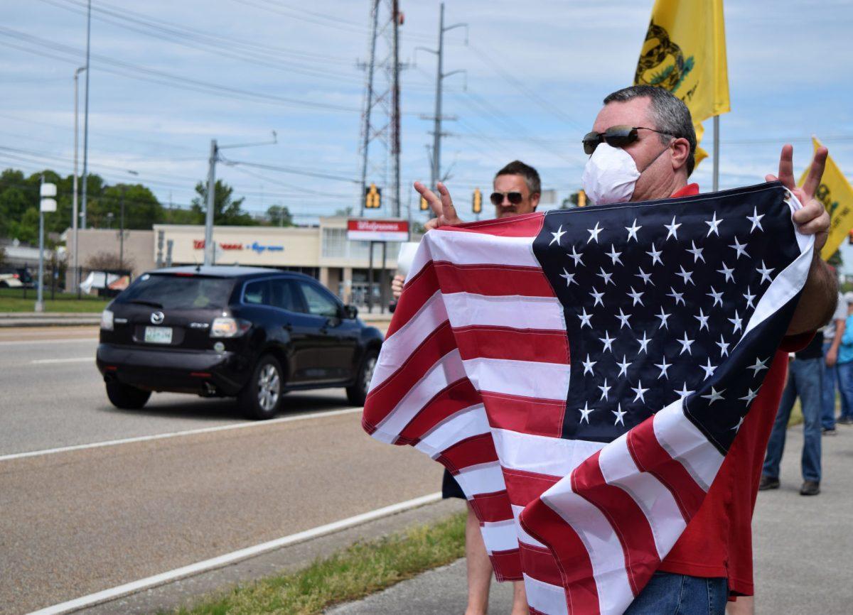 A protester holds up an American flag along Kingston Pike during the Knoxville Freedom Rally outside the closed West Town Mall on Sunday, April 19, 2020.