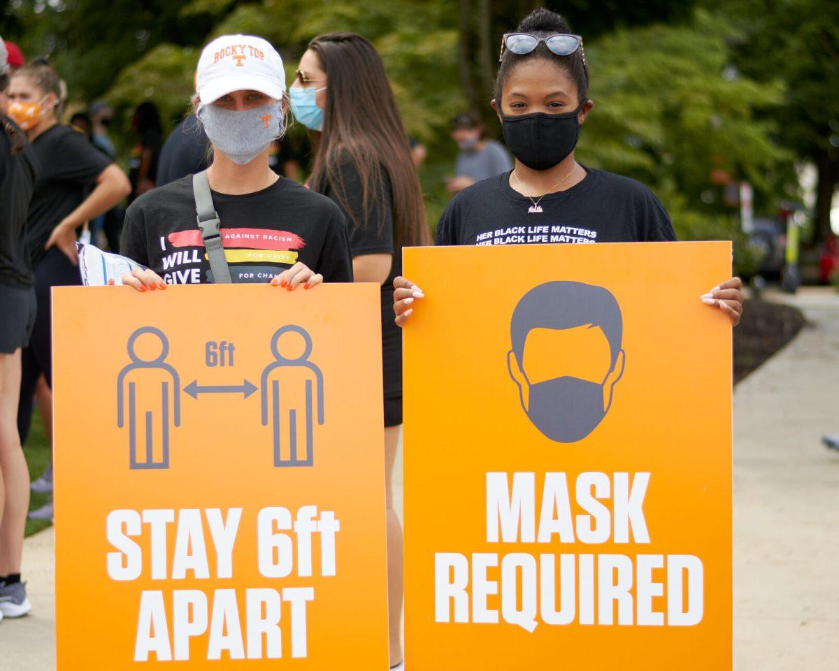 Two students pose in Circle Park holding signs requiring participants of the BLM March to maintain social distancing, and to wear a mask at all times, on August 29, 2020.