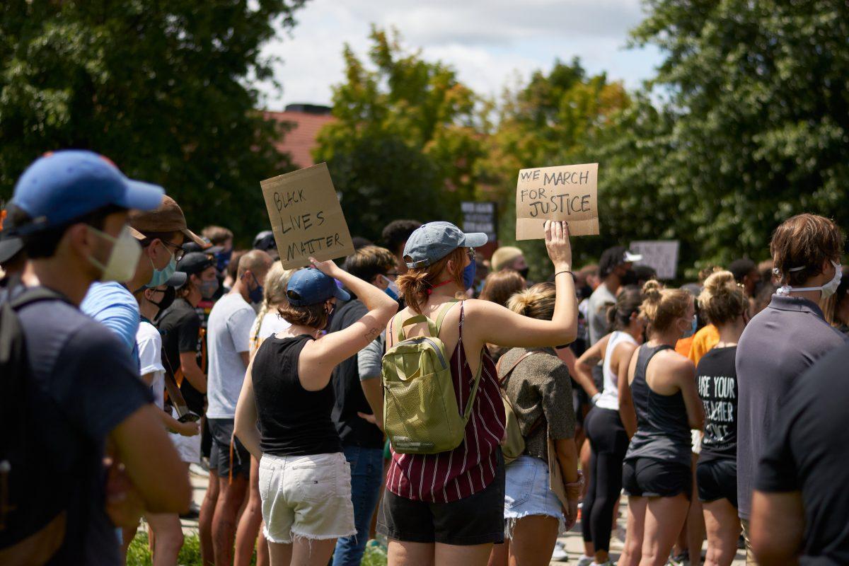 Two supporters hold signs while listening to speakers at Ayres Hall, at the end of the BLM March on August 29, 2020.
