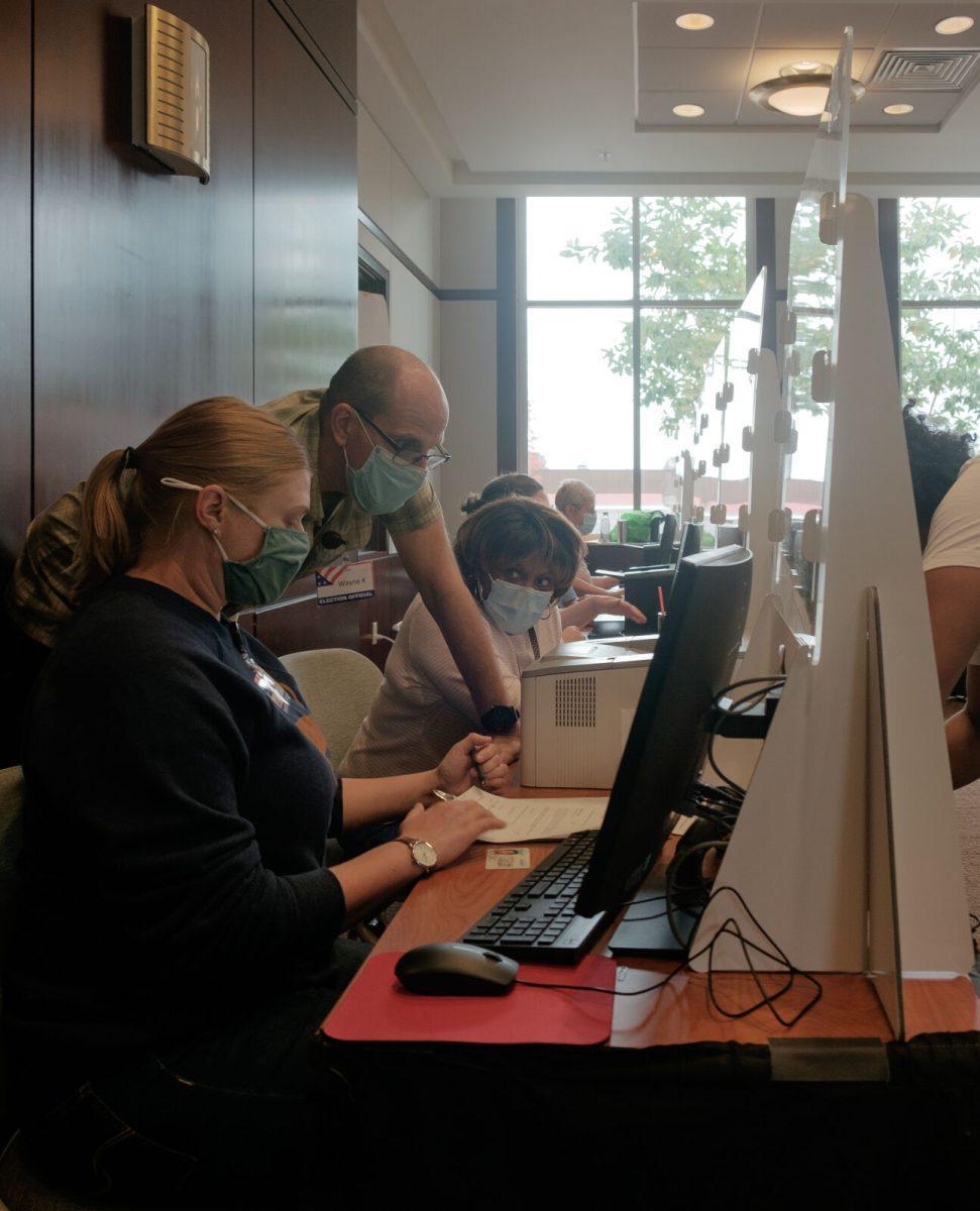 Poll workers assist a voter on their forms at Howard Baker Jr. Center on Oct. 26, 2020.