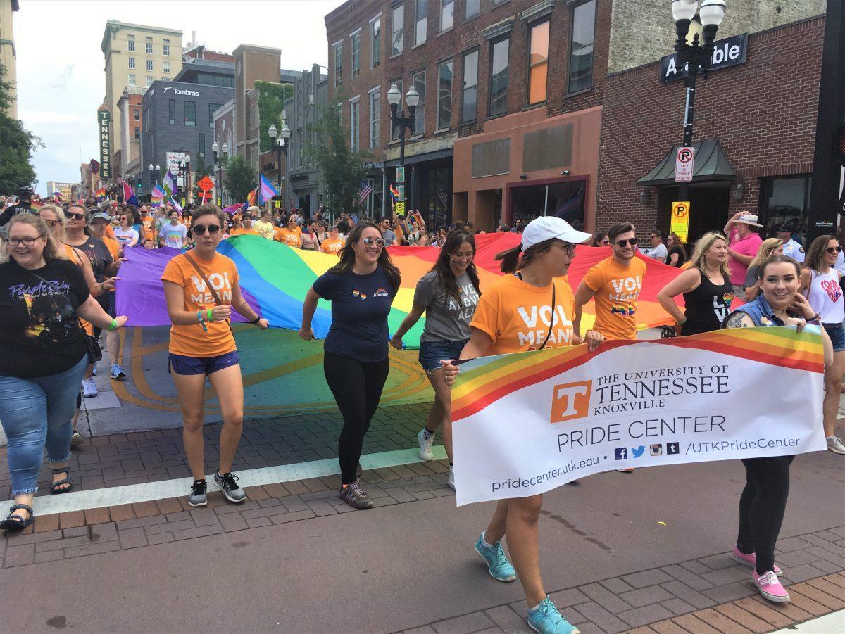 Members of UT's Pride Center carry a large LGBTQ flag down Gay Street. 