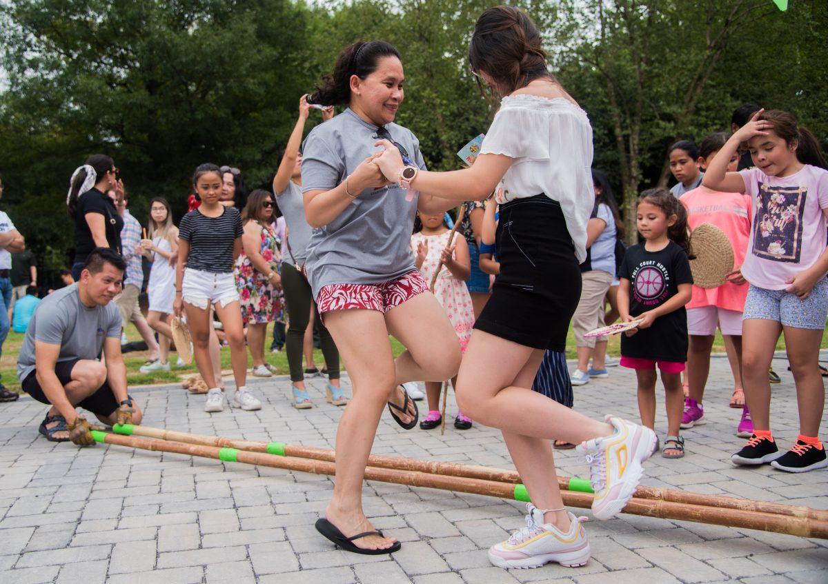 A member of the Philippines booth teaches an attendee a traditional dance at the Knoxville Asian Festival at World's Fair Park on August 25, 2019. 
