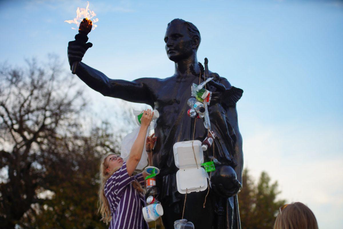 KNOXVILLE, TN - Plastic Free UT co-founder Rachel Stewart blouses the UT Torchbearer with plastic containers in protest of single use plastics on campus for International Day of Climate Action. Monday, Oct. 24, 2022. 