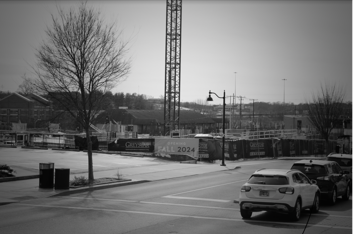 A construction fence on Cumberland Avenue projects an opening date for expansive new apartments to meet the campus housing shortage.