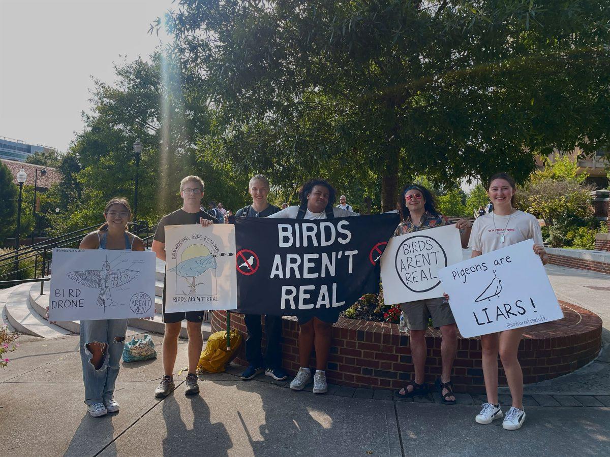 Students with the UT student organization Birds Aren't Real protest on PED walkway.