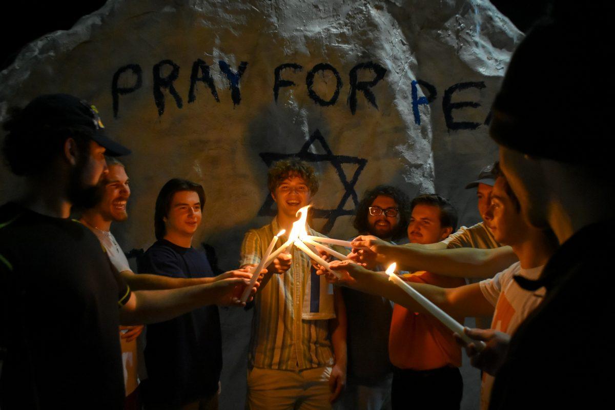Members of the Jewish fraternity, Alpha Epsilon Pi, light their candles together in front of their message. Thursday, Oct. 12, 2023.