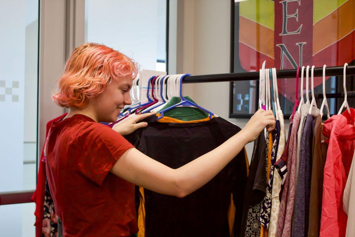 Zoe Trainor, a junior majoring in English, sorts through a rack of clothes on pop up in the Pride Center. Wednesday, Oct. 11, 2023.