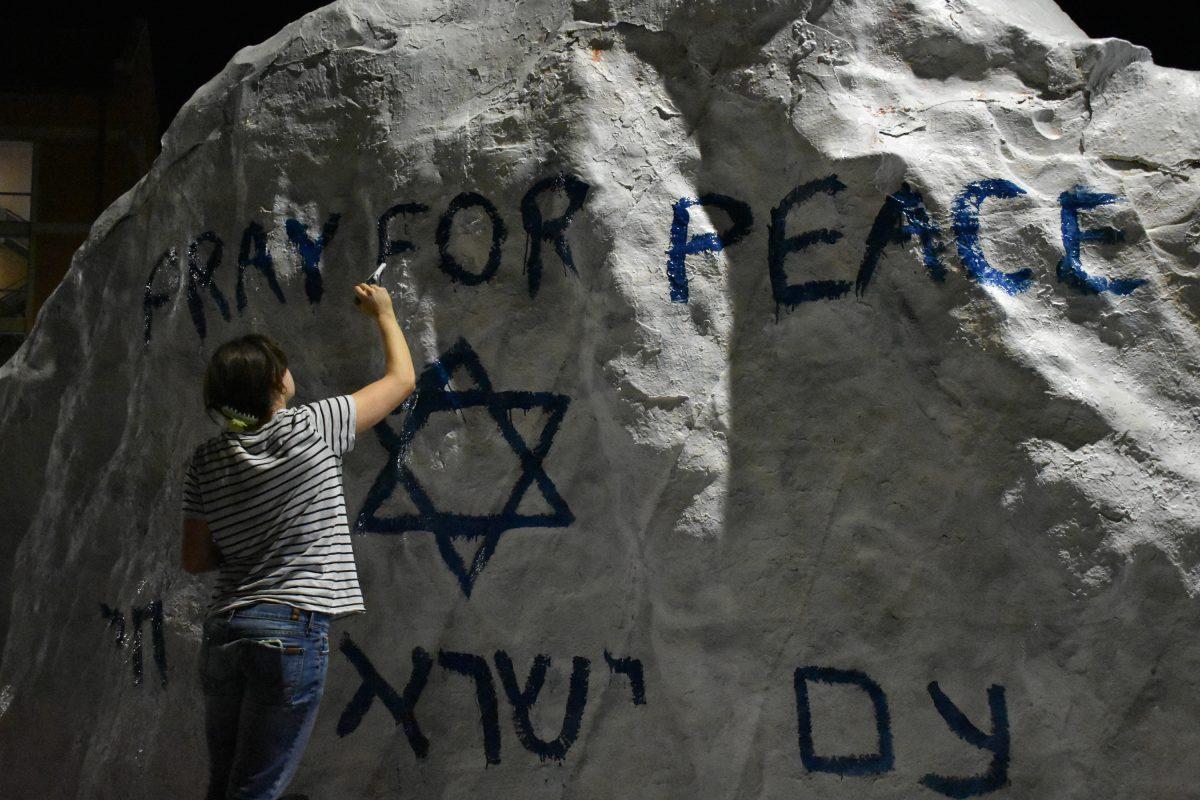 A student paints the Rock in memoriam of those who were killed in the Hamas attack. Thursday, Oct. 12, 2023.