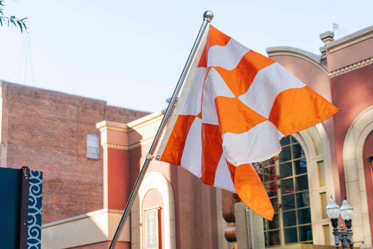 Volunteer Fan waives a checkerboard flag during the National Champion Volunteers parade. Tuesday, June 25, 2024.