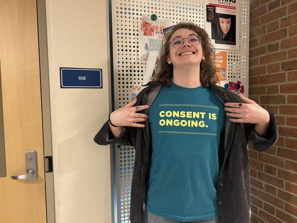 Carver Dickens poses with his “Consent Is” project t-shirt in front of the room where College Republicans were expected to meet. Thursday, Feb. 6, 2025. 