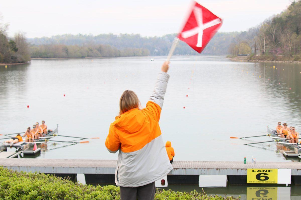 Coach Violette Legrand holding the flag at the starting line of the regatta against Stanford University on Melton Hill Lake. Saturday, March 29, 2025.