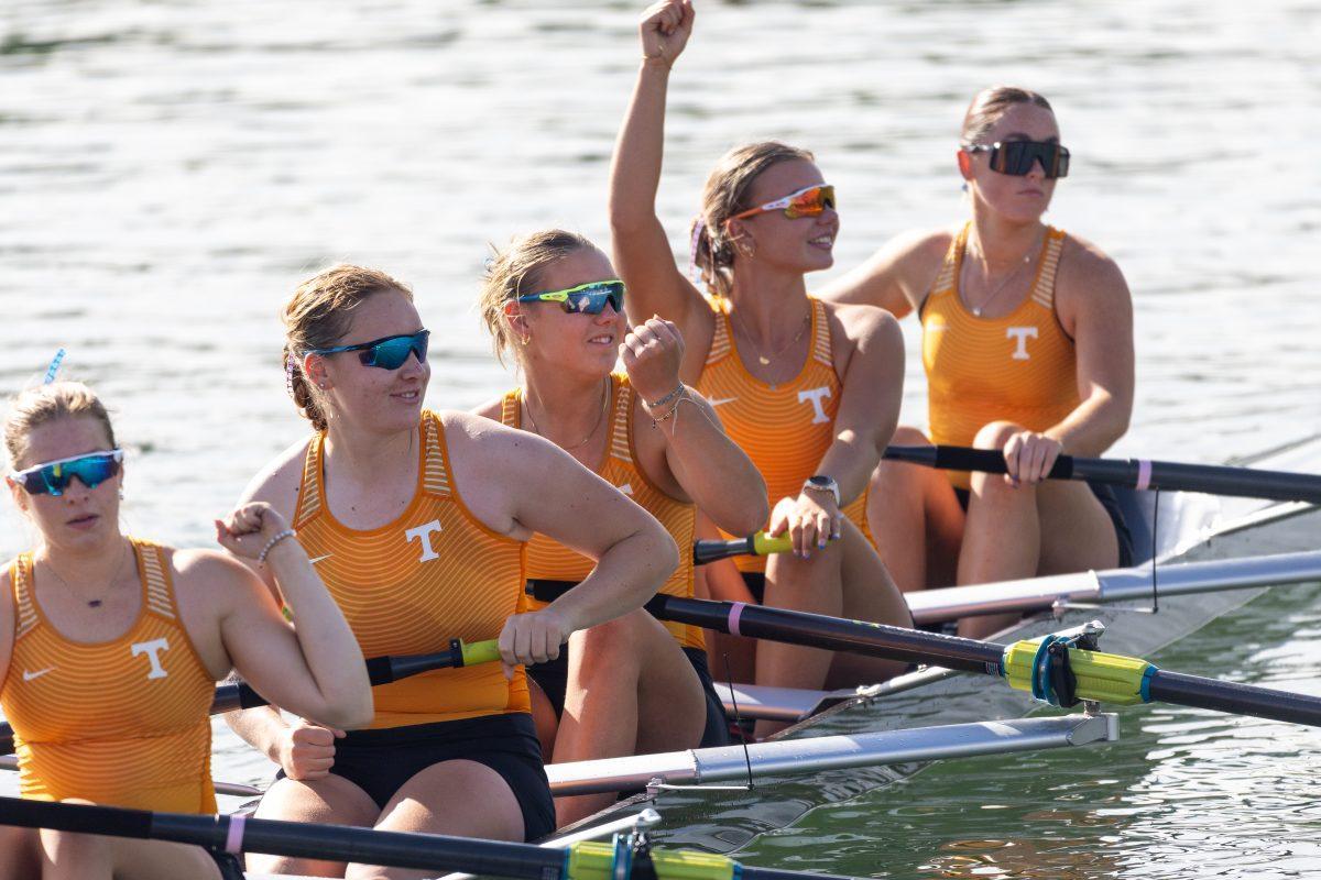 (From left to right) Rowers Emma Flanagan, Megan Wood, and Ava Mulholland smile and wave to Coach David Hall who yells from the shoreline at the SEC Championship on Melton Hill Lake. Sunday, May 11, 2025.